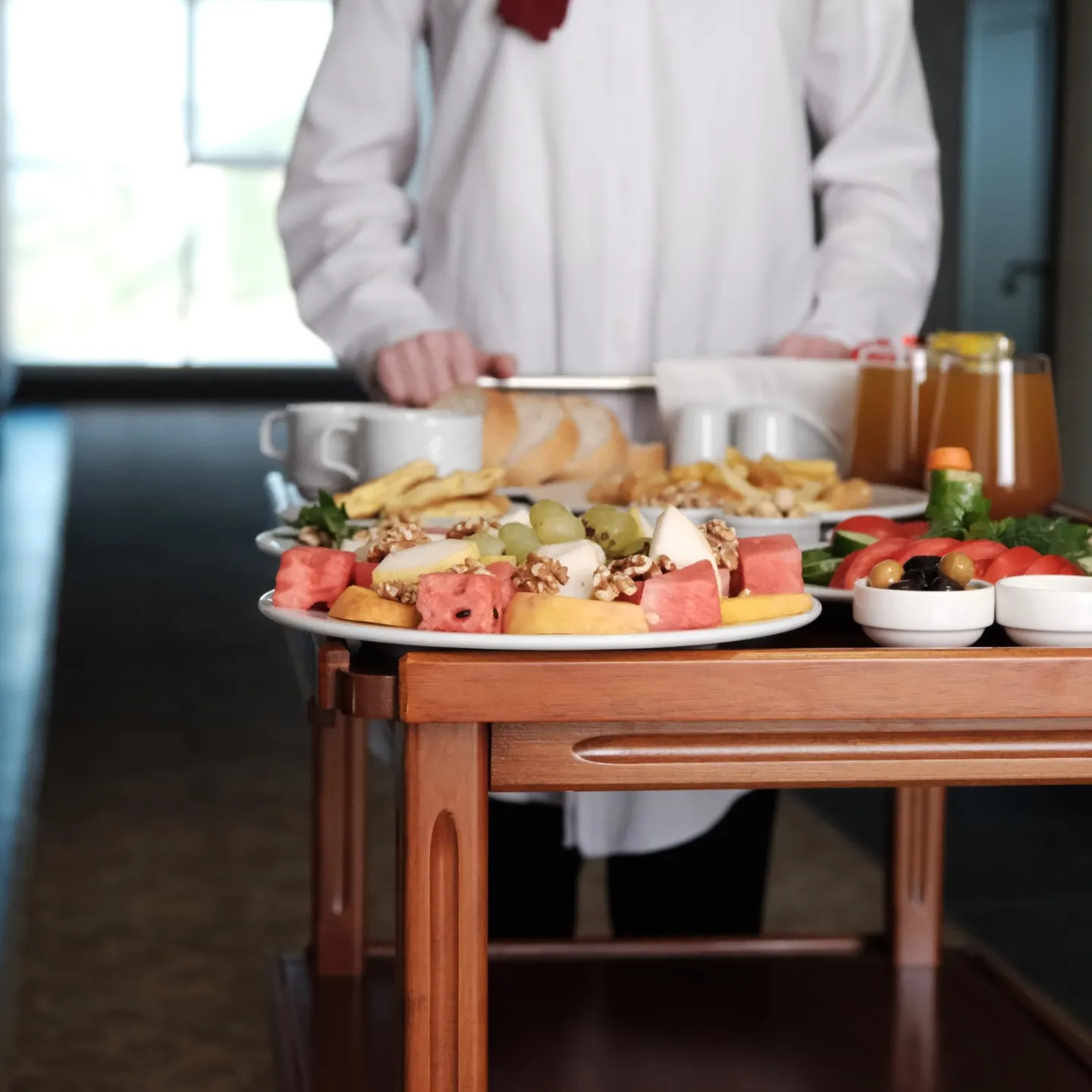 Peynir, zeytin, meyve ve içecekler dizilmiş oda servisi arabası